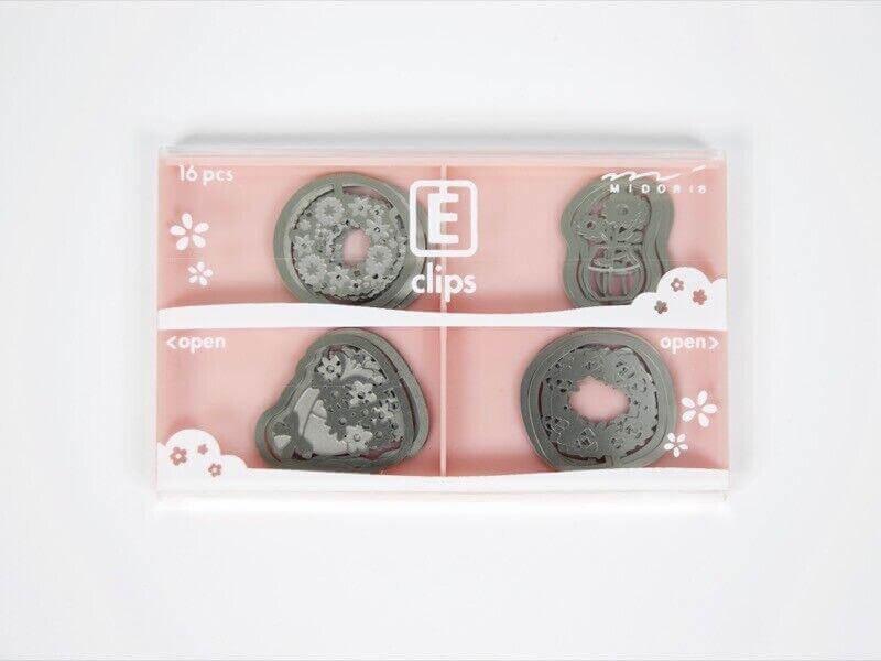 Set of 16 decorative steel E-clips in assorted shapes for paper and office use in a pink box.