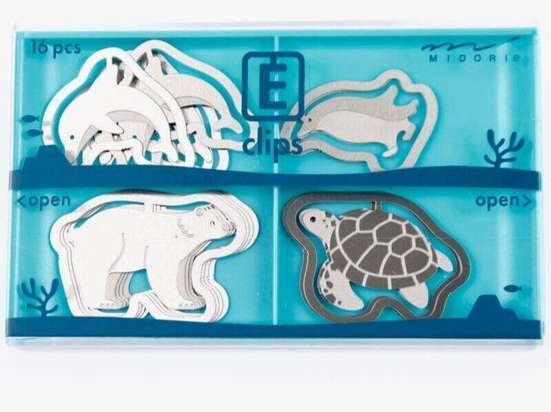 Assorted animal-shaped steel paper clips in a blue plastic organizer, featuring polar bear, dolphin, sea turtle designs