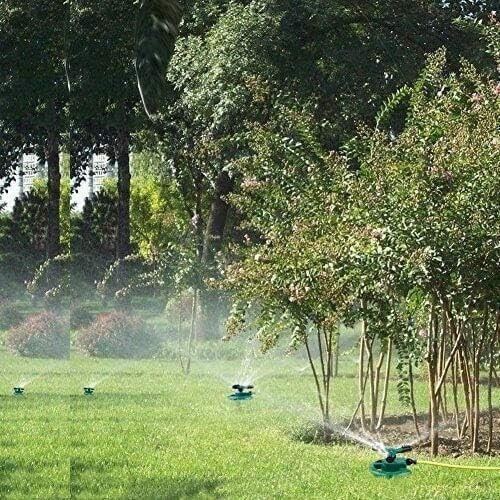 Green lawn sprinklers watering grass and trees in a garden