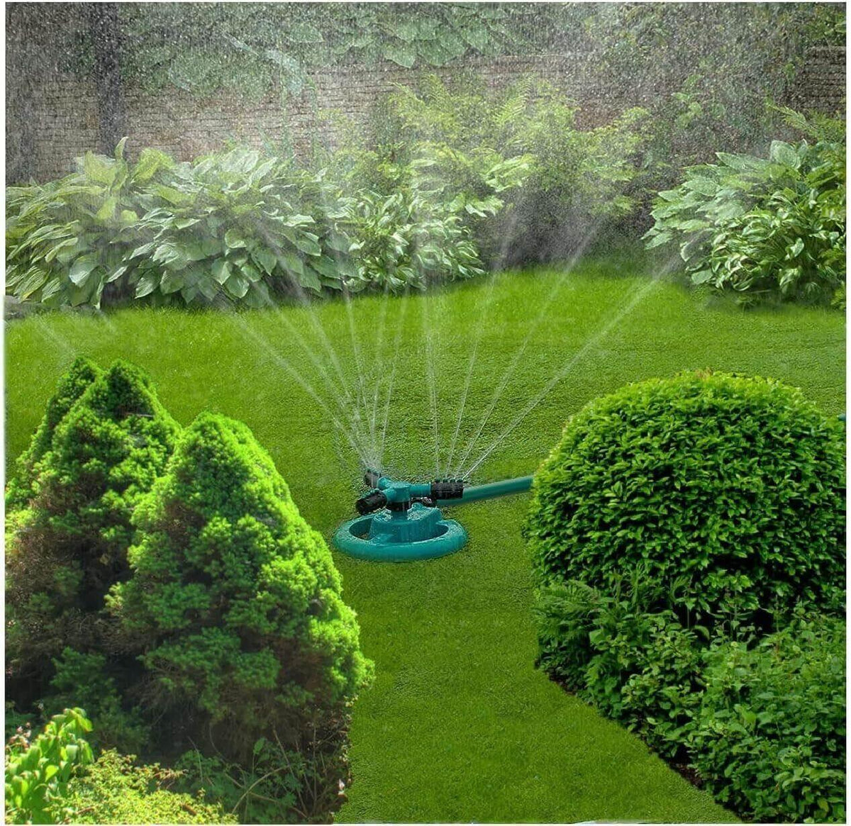 Green oscillating lawn sprinkler watering lush grass and garden shrubs in backyard