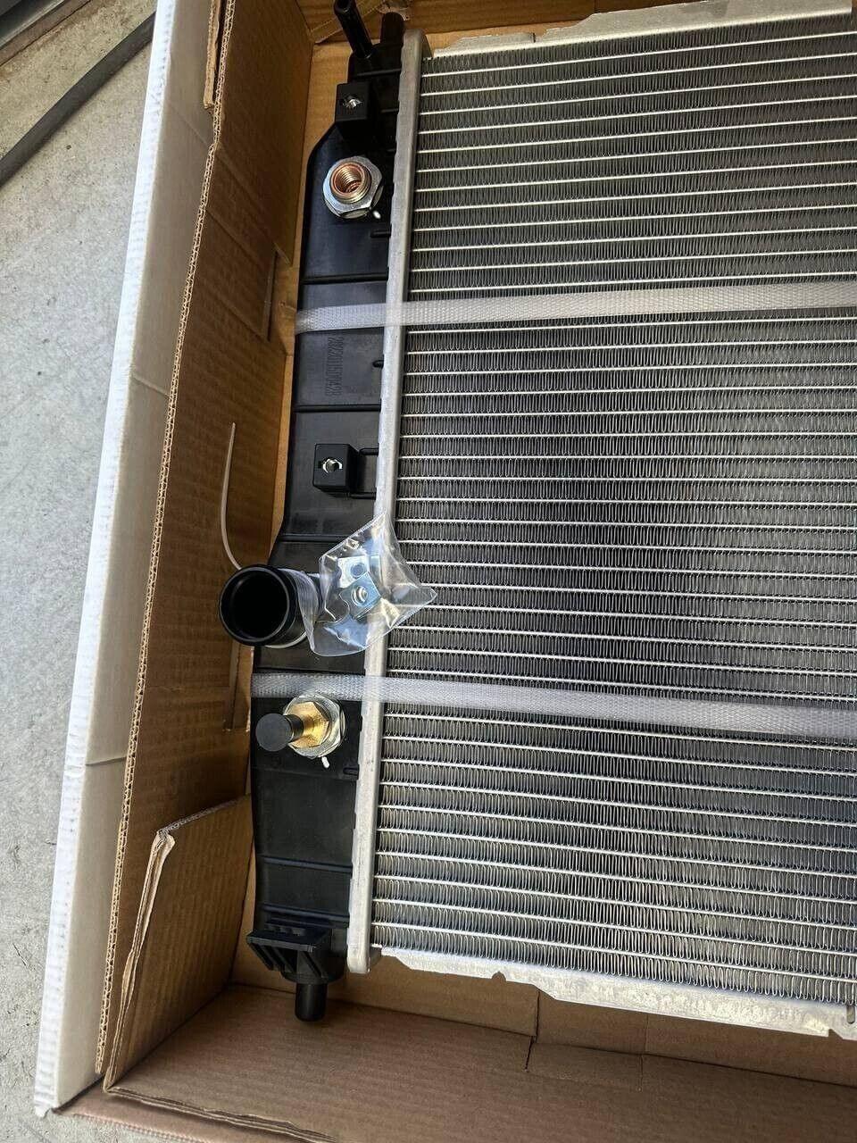 New tractor radiator with black tank and fittings, packed in cardboard box for shipping