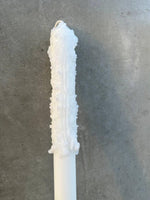 White textured candle with rough wax surface against gray background