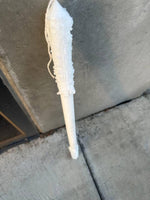 White candle with textured wax drips on concrete surface