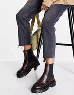 Brown leather Chelsea boots with chunky soles paired with cropped jeans