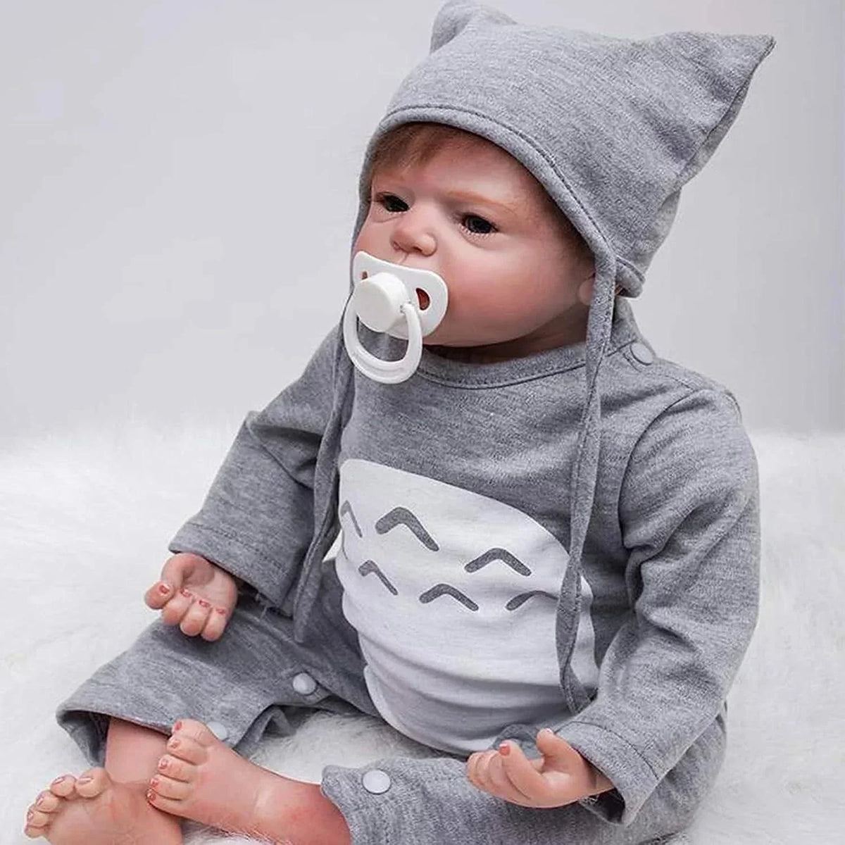 Baby doll in gray cat-ear hoodie with pacifier, realistic features, soft fabric design