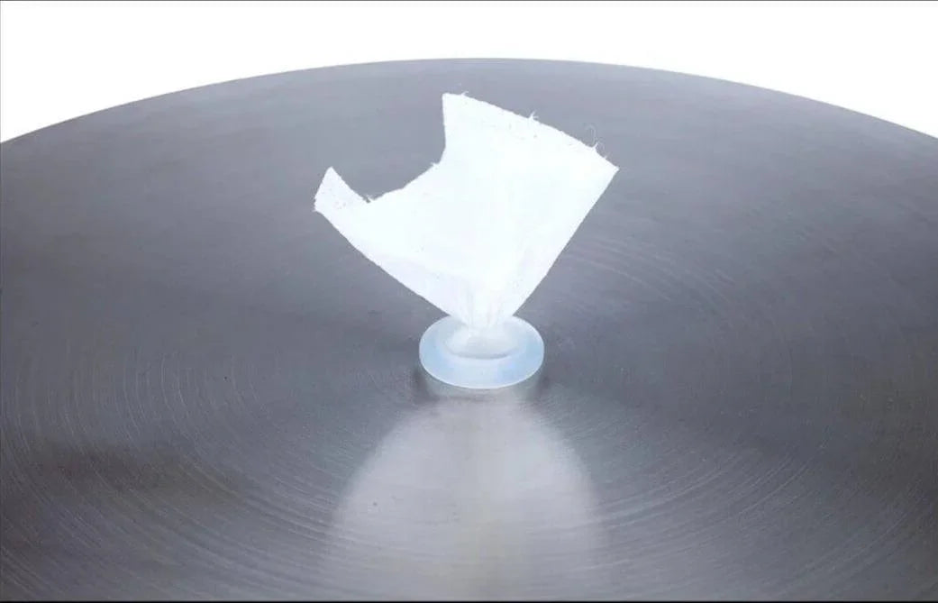 White plastic suction cup with torn paper on metallic surface