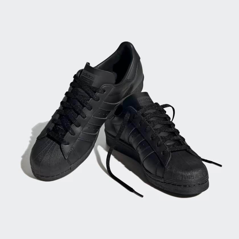 Black Adidas Superstar sneakers with classic shell toe design and three stripes, all-black casual footwear