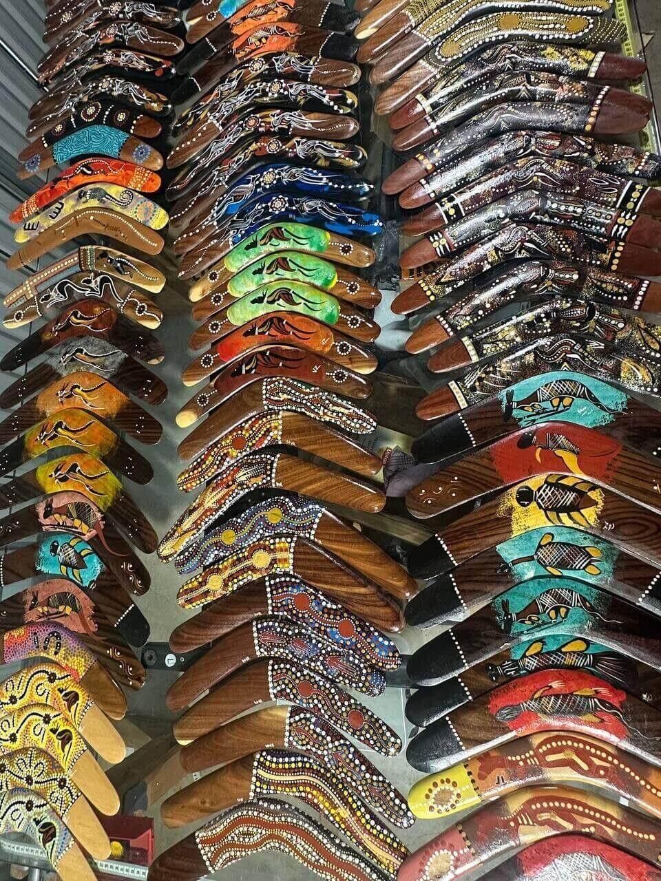 Colorful hand-painted boomerangs with Aboriginal art designs displayed in rows