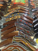 Colorful hand-painted boomerangs with Aboriginal dot art, wooden craftsmanship, decorative collectibles