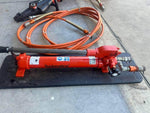 Holmatro hydraulic rescue tool with orange hoses, used for vehicle extrication and heavy-duty lifting.