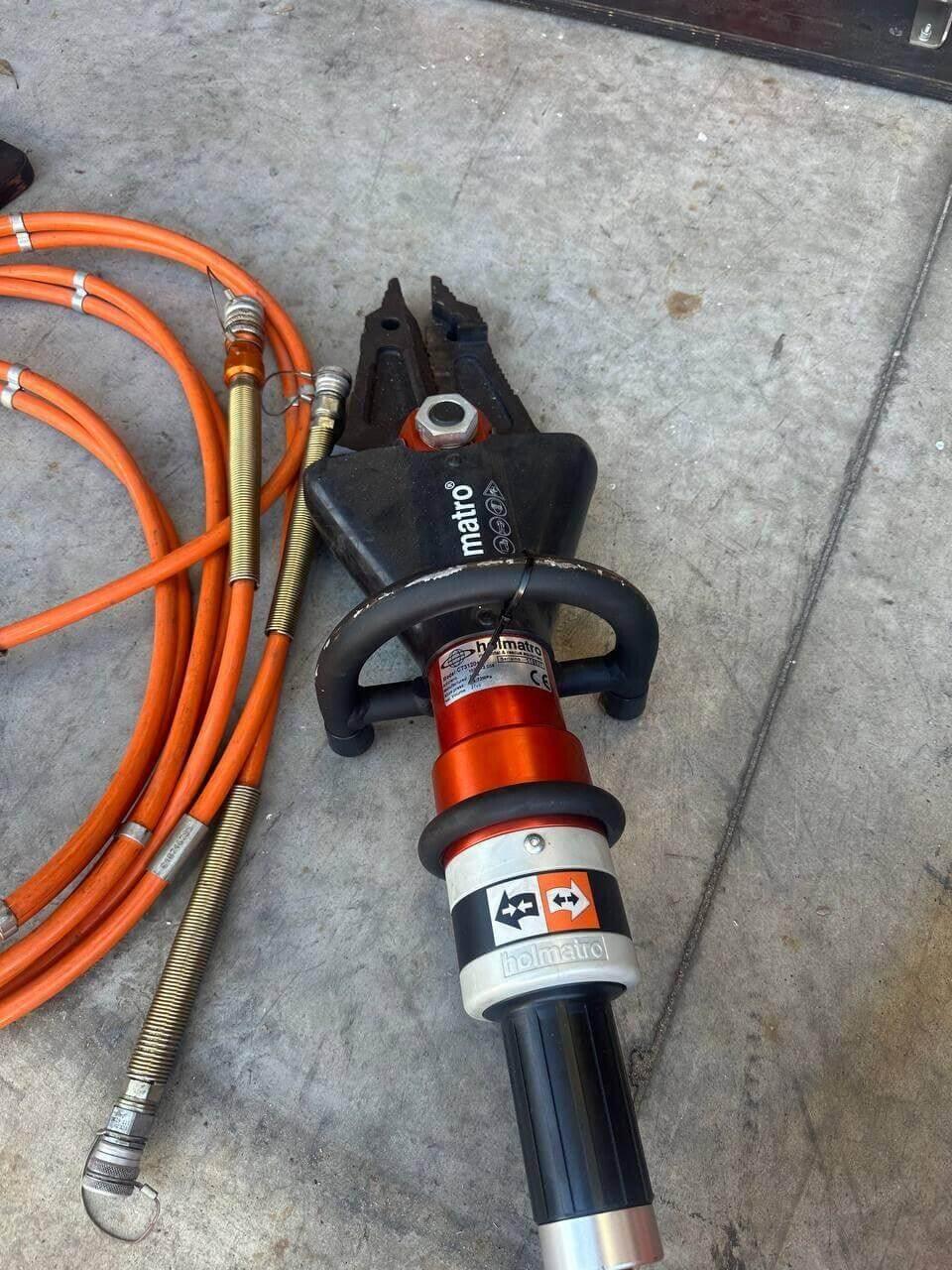 Holmatro Matro hydraulic rescue tool with orange hoses on concrete floor