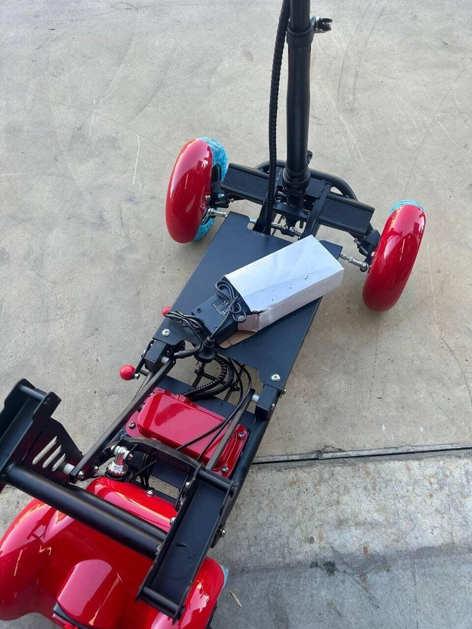 Red electric scooter with black frame, visible battery, and blue-tinted wheels on concrete