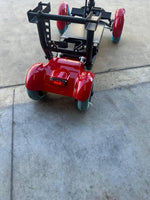 Red mobility scooter with blue wheels on concrete surface