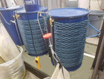 Blue industrial drums with heating wraps and fluid transfer hoses in workshop setting