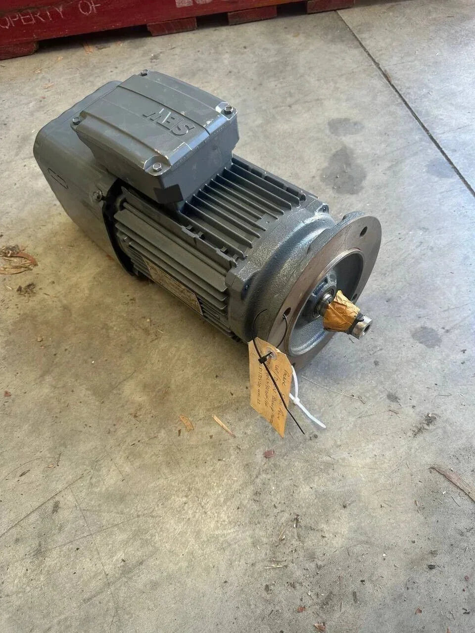 Industrial electric motor with tag, suitable for tractor or truck parts, warehouse setting