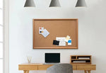 Wooden desk with corkboard, laptop, and office supplies in a bright workspace