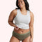 Woman wearing olive green underwear and gray tank top, showcasing comfortable plus-size lingerie