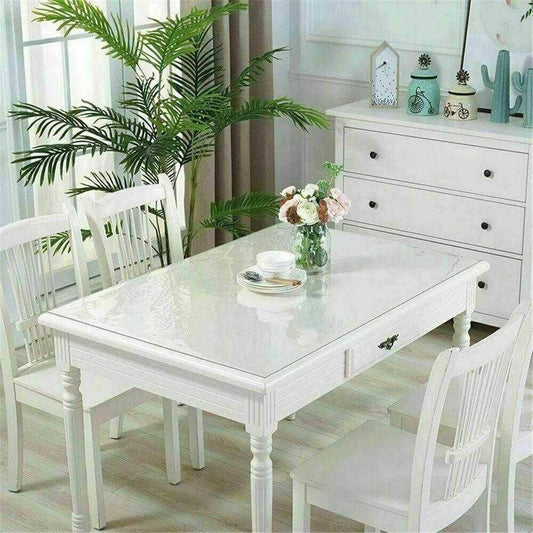 Clear PVC tablecloth plastic table cover on white dining table with chairs in bright room