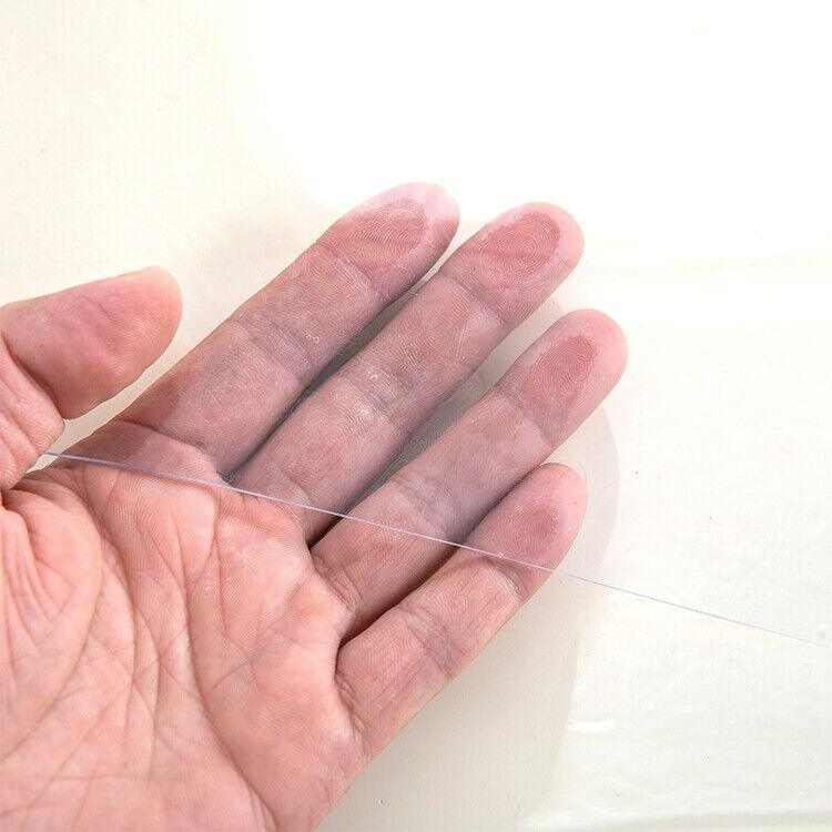 Hand holding a clear PVC plastic tablecloth cover for dining table protection