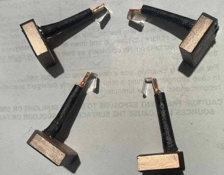 Set of four replacement carbon brushes for tractor or automotive alternators on a plain background.