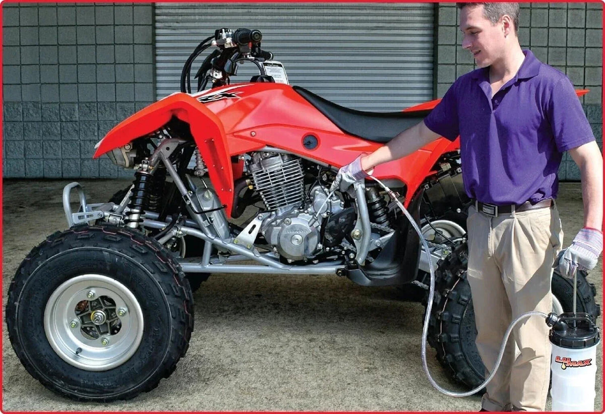 Man maintaining red ATV with engine exposed, using lubricant spray, outdoor garage setting