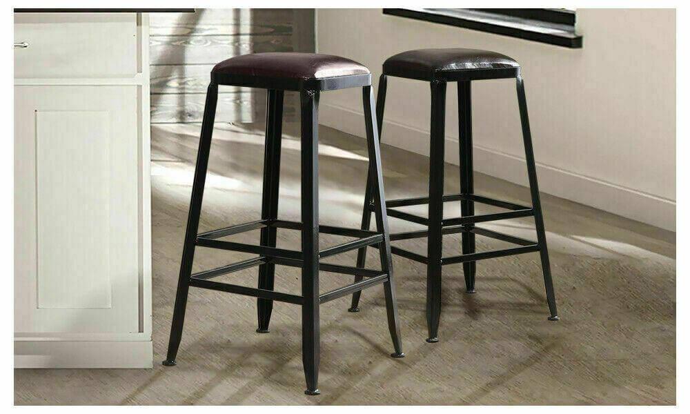 Pair of industrial bar stools with black metal frames and brown leather seats in kitchen setting