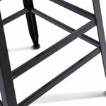 Close-up of black metal bar stool legs and footrest on white background