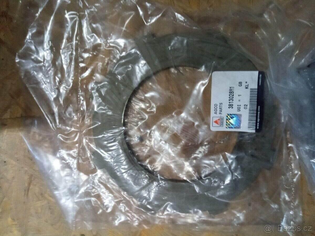 Metal tractor plate part labeled 3813028M1 in clear plastic packaging on wooden surface