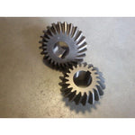 Two metal bevel gears for tractor or machinery parts on a gray surface