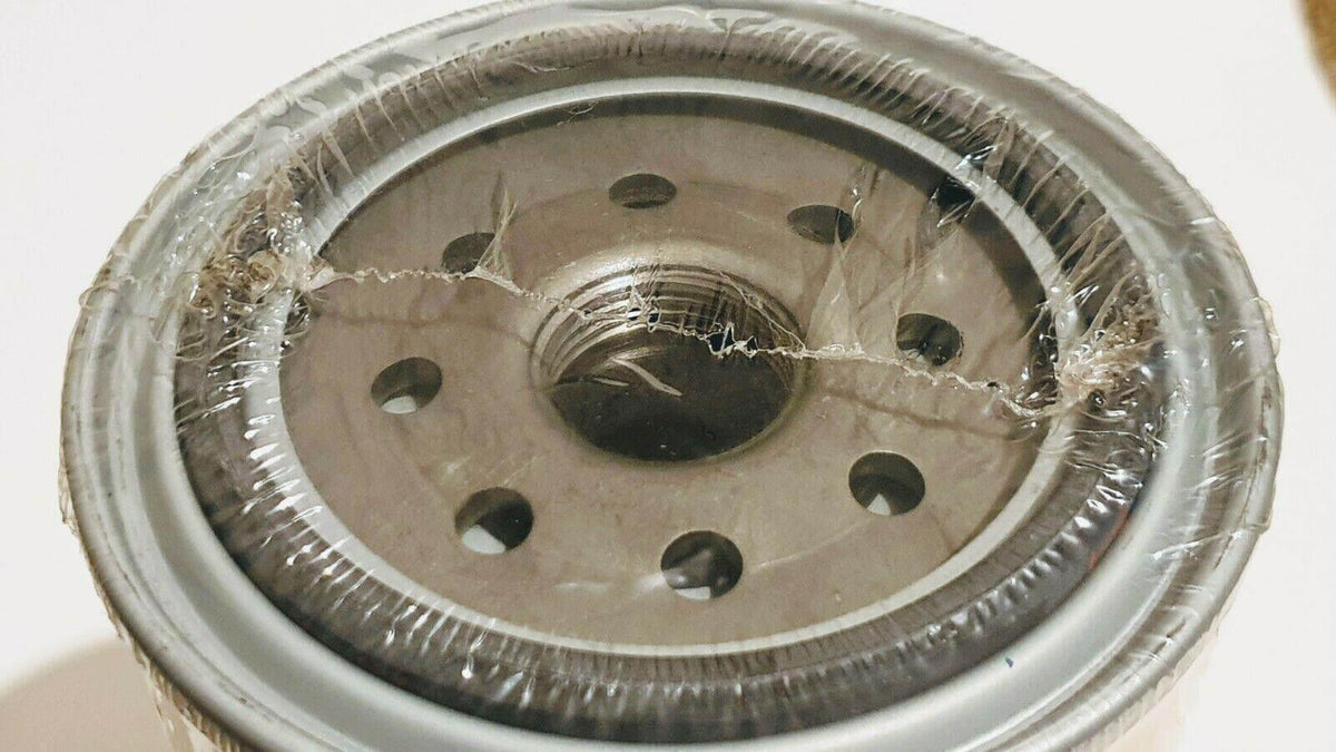Close-up of a sealed metal fuel filter with circular openings and protective wrap