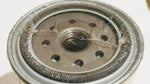 Close-up of a sealed metal fuel filter with circular openings and protective wrap