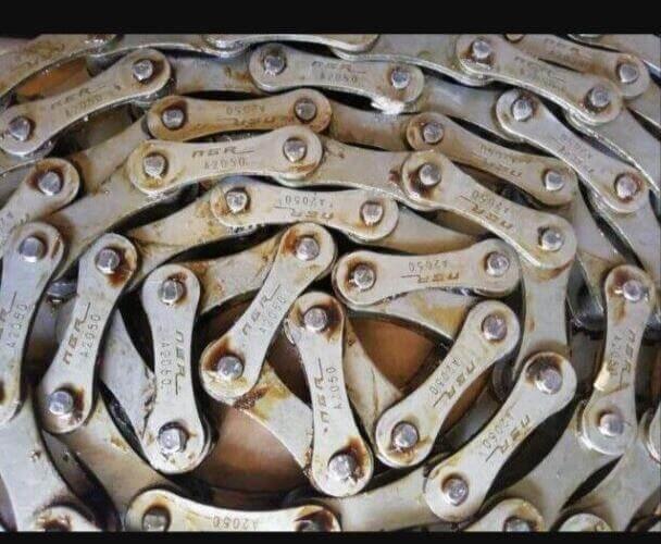 Close-up of a metal drive chain for tractors, showcasing interlocking links and silver finish.