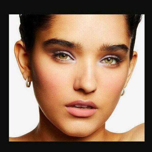 Close-up of woman with glowing peach blush, soft pink lips, and shimmery eye makeup