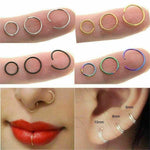 Assorted surgical steel hoop rings in silver, gold, black, and rainbow colors for nose, lip, and ear piercings, shown in various sizes.