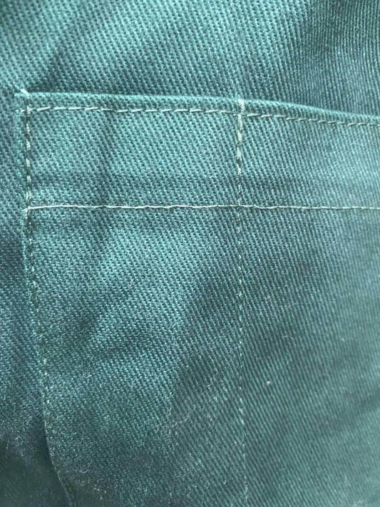 Close-up of bottle green cotton drill fabric with pocket stitching on men's coveralls