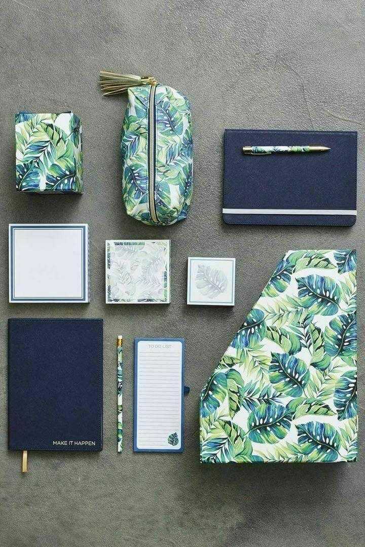Tropical leaf print stationery set with pencil case, folders, notebooks, and notepads on gray background