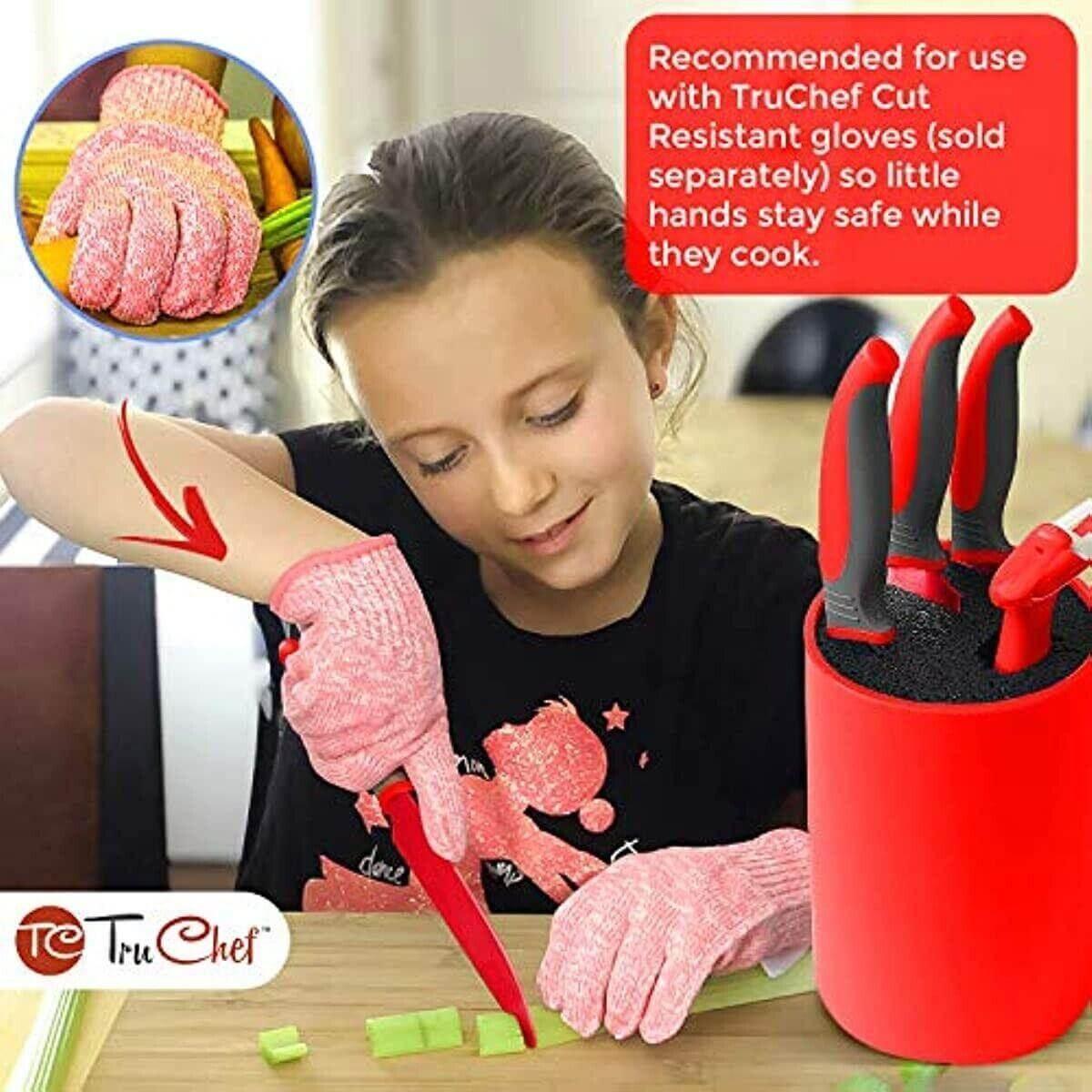 Child wearing cut-resistant gloves using red kids knife set to cut vegetables, knife block nearby