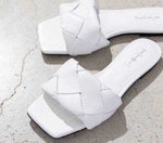 White quilted leather women's wedge slide sandals with open toe on a concrete surface