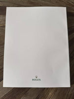 White Rolex box with crown logo on wooden surface, luxury watch packaging