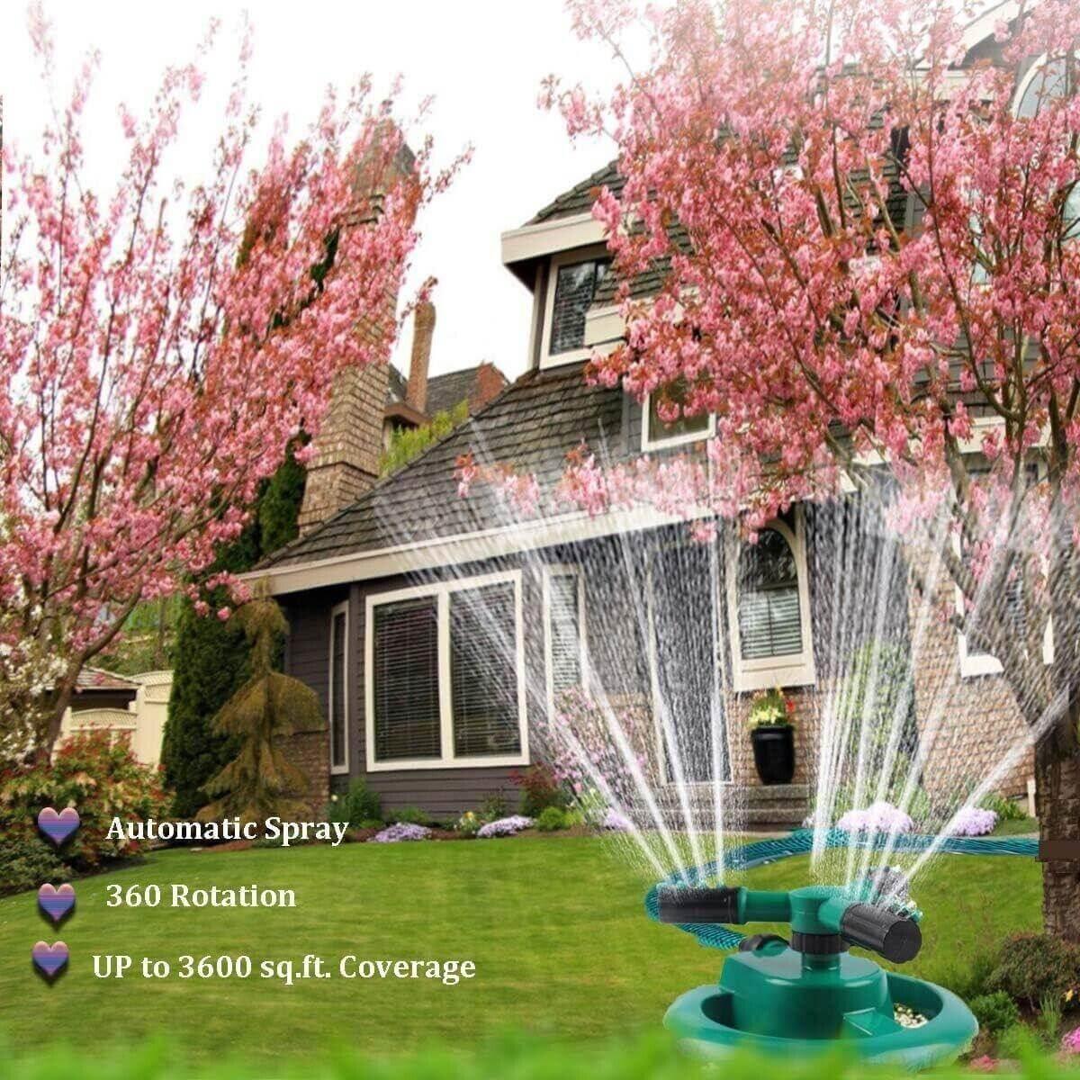Automatic 360° rotating lawn sprinkler spraying water on green grass with blooming pink trees and house background