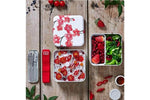 Cherry blossom lunchbox with fresh salad, berries, and utensils on rustic wood