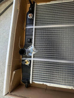 New tractor radiator with black tank and fittings, packed in cardboard box for shipping