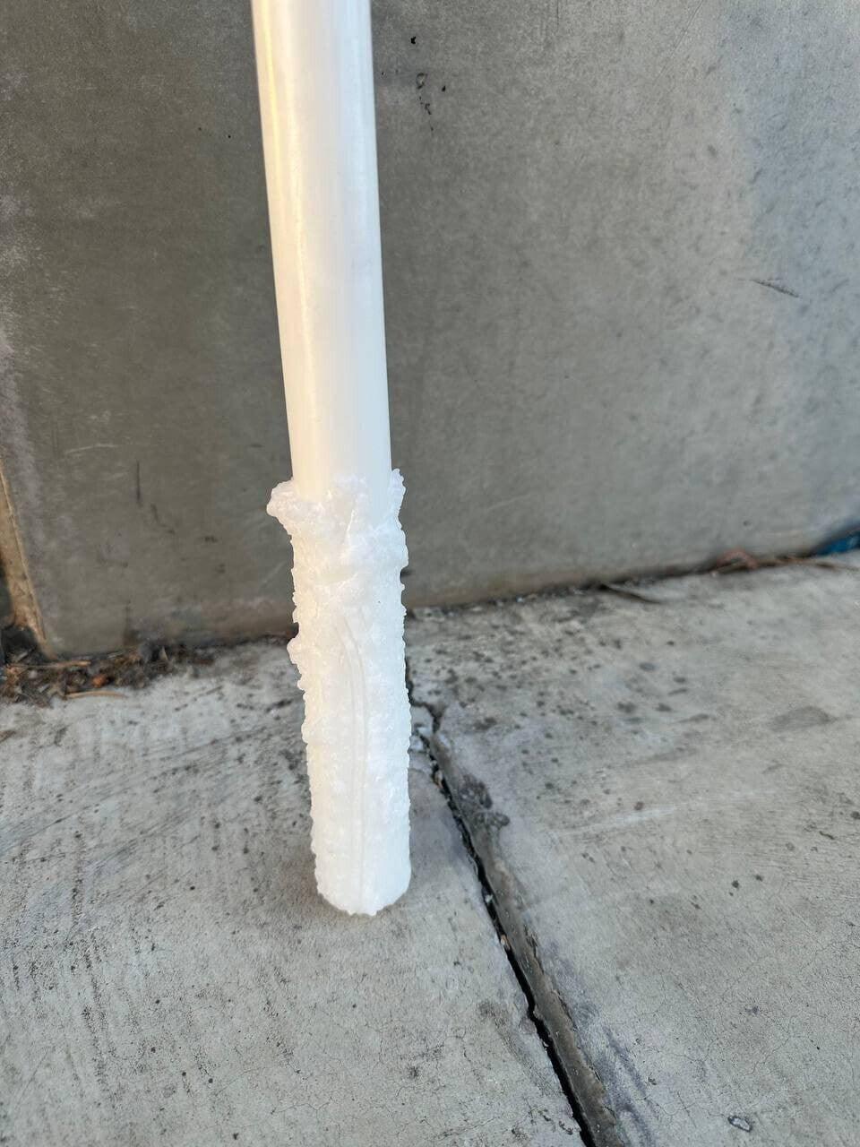 White plastic pipe with textured foam insulation against concrete background