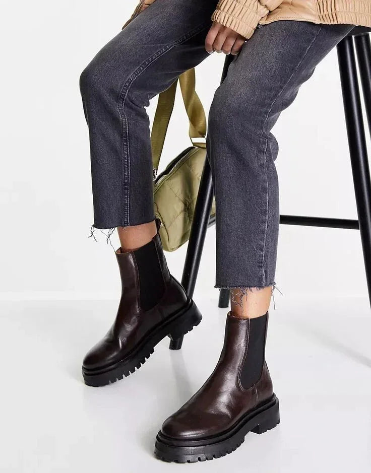 Brown leather Chelsea boots with chunky soles paired with cropped jeans