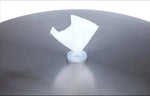 White plastic suction cup with torn paper on metallic surface