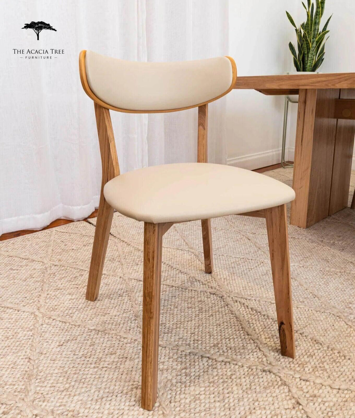 Modern wooden dining chair with cream upholstered seat and back, styled in minimalist home setting