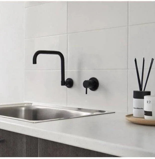 Modern black wall-mounted kitchen faucet with sleek design on white countertop