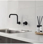 Modern black wall-mounted kitchen faucet with sleek design on white countertop