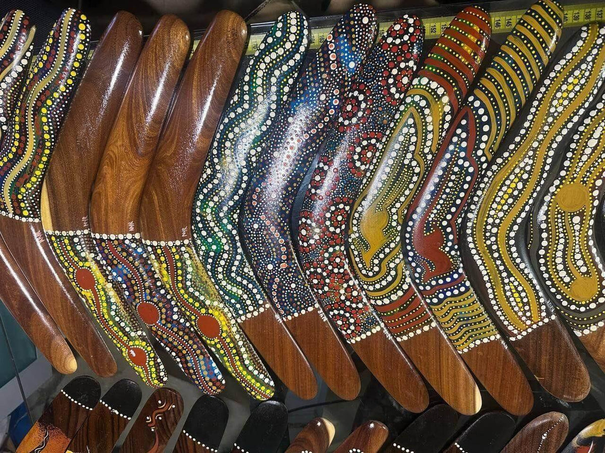 Colorful Aboriginal boomerangs with dot art designs, wooden handles, and vibrant patterns