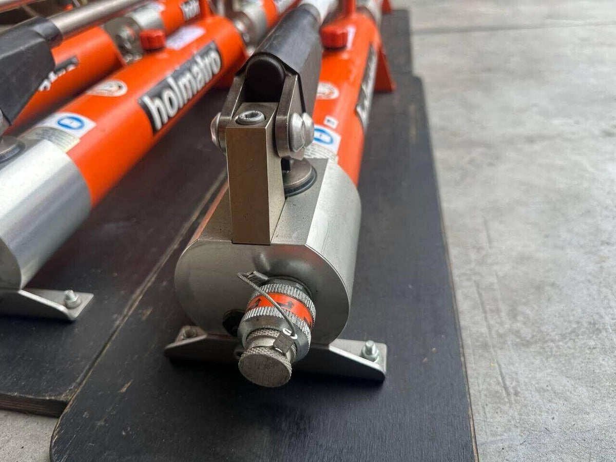 Orange Holmatro hydraulic rescue tool with metal fittings and black base
